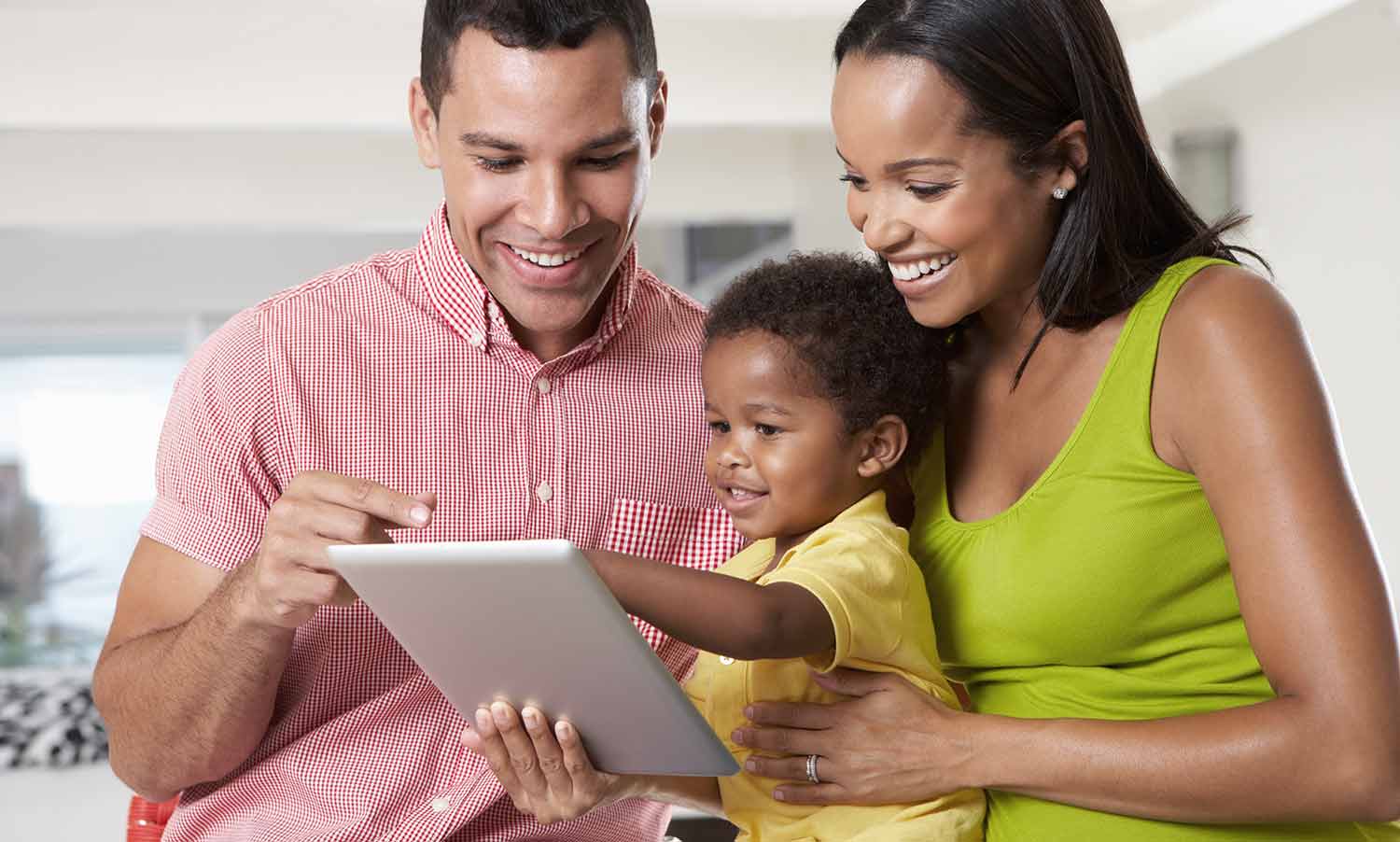 Parents holding Toddler looking at tablet