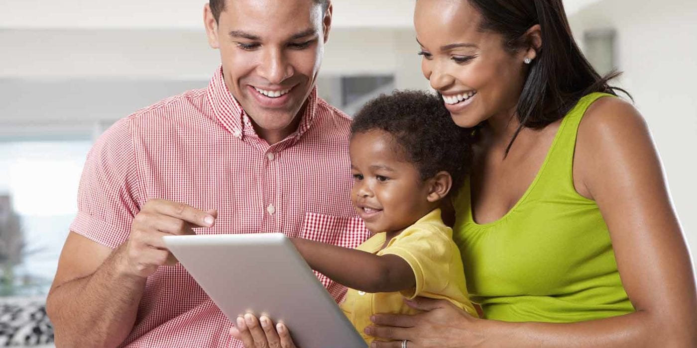 Parents holding Toddler looking at tablet