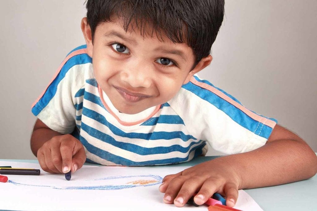 Preschool boy coloring at table