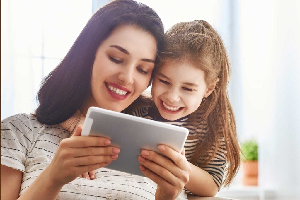 Mom and child looking at daycare news on tablet