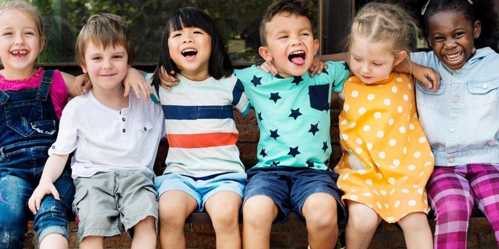 Daycare group of kids hugging and sitting on bench